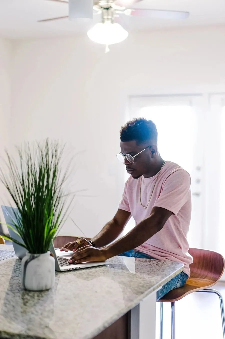A man studying on a laptop at a kitchen bench
